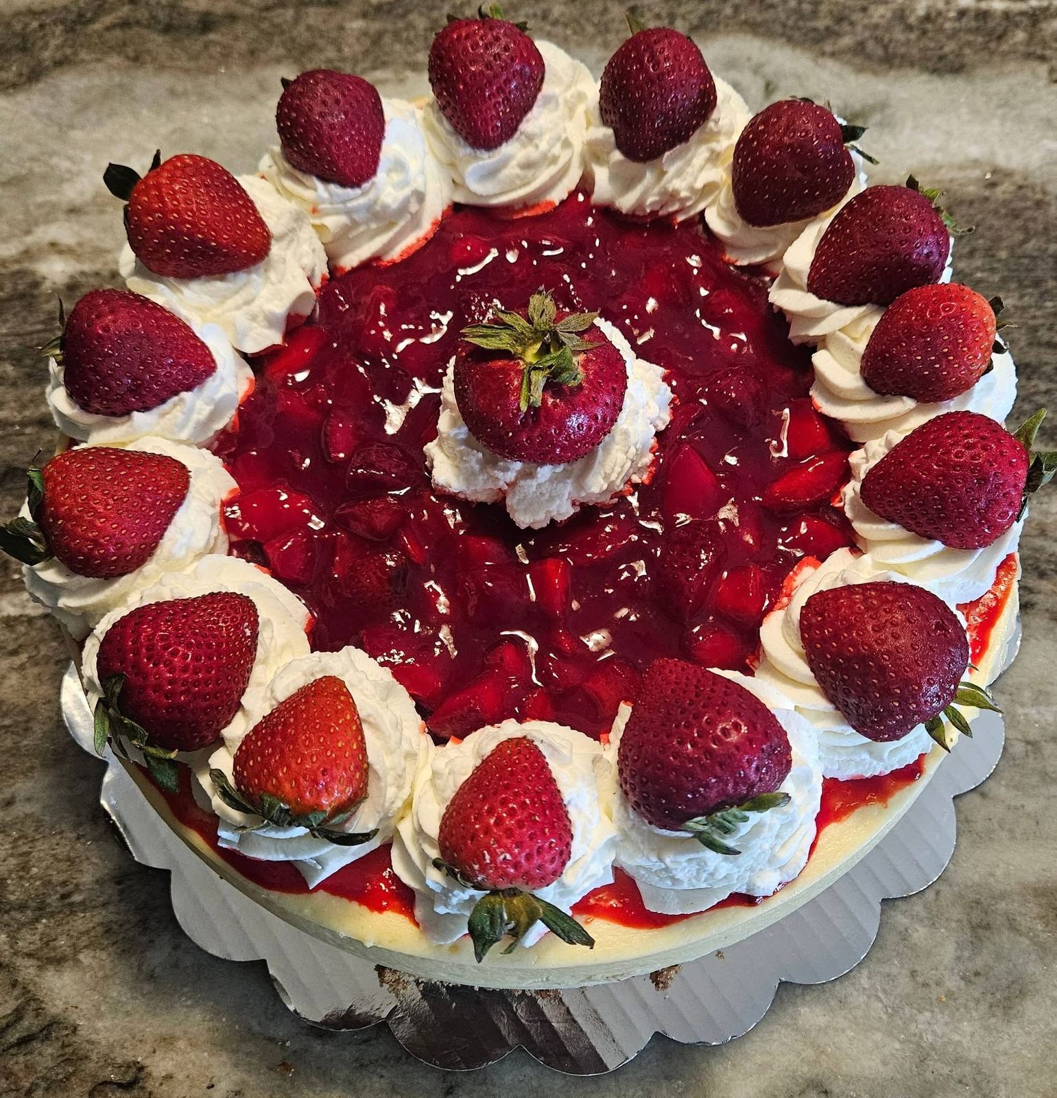 Strawberry cheesecake topped with fresh whole strawberries and whipped cream