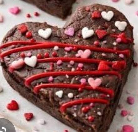 Heart-shaped fudge brownie with red drizzle and candy hearts